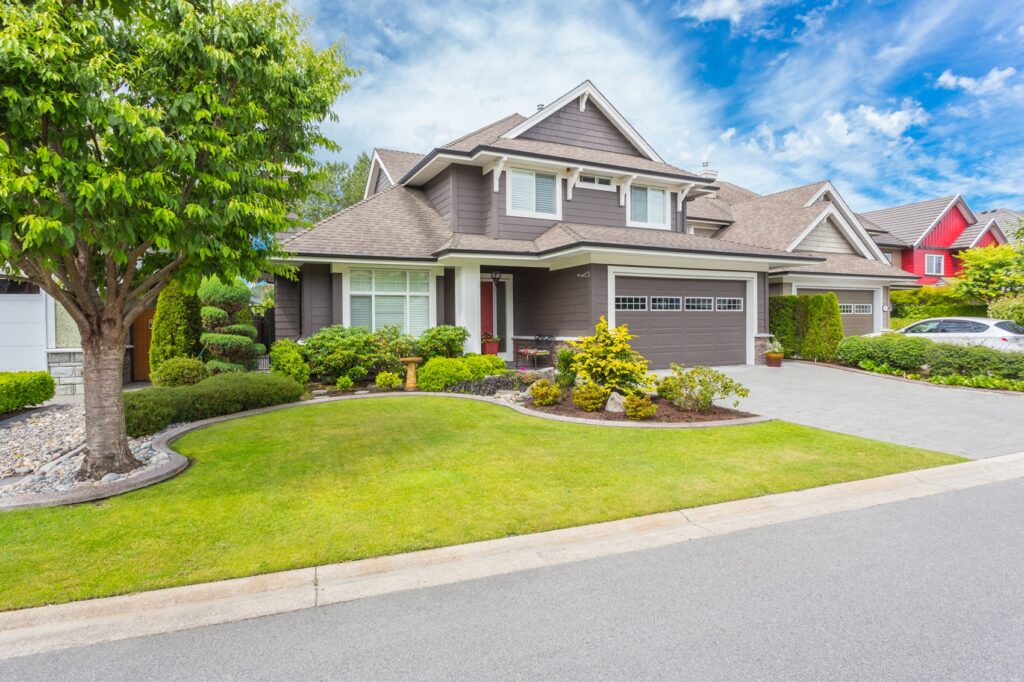 A brown house with a manicured front yard on a sunny day.