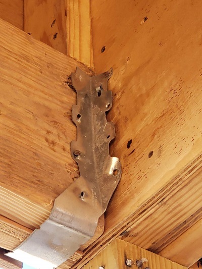 A close-up of a home's wooden framing shows a metal hanger is missing its fasteners.