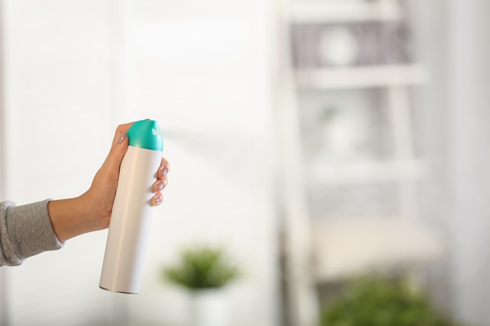 A handheld air freshener is sprayed inside a home.