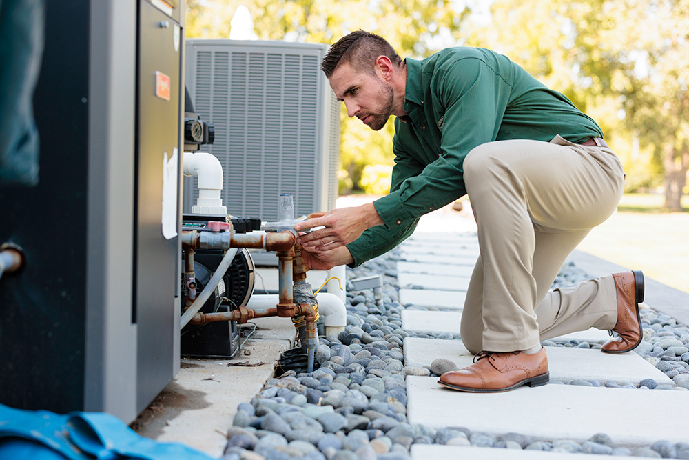 An NPI inspector examines piping and utilities on the exterior of a building.